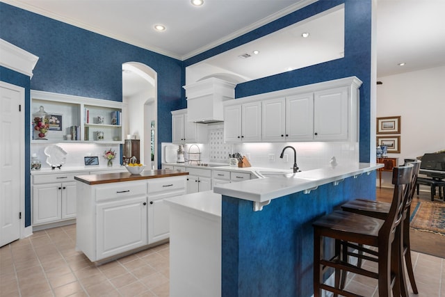 kitchen with sink, white cabinetry, backsplash, a kitchen breakfast bar, and kitchen peninsula