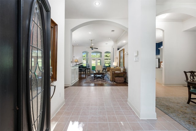 foyer featuring light tile patterned flooring, ceiling fan, and crown molding