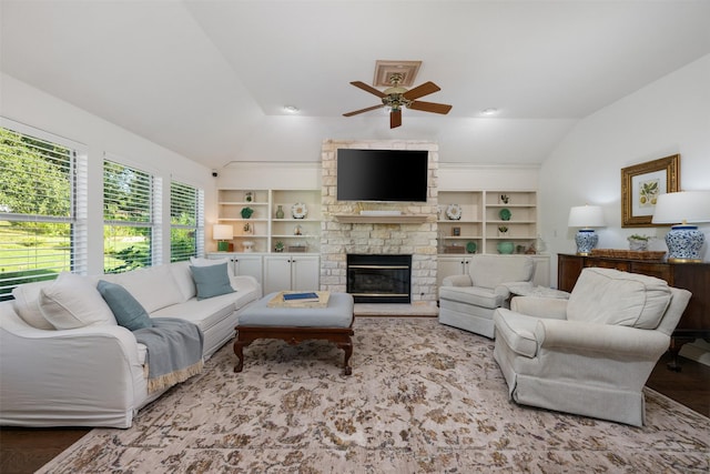 living room with ceiling fan, a fireplace, vaulted ceiling, and built in features