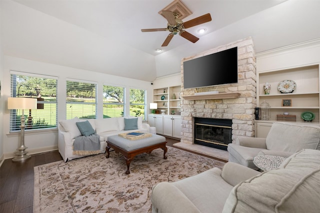 living room featuring vaulted ceiling, a stone fireplace, hardwood / wood-style floors, built in features, and ceiling fan