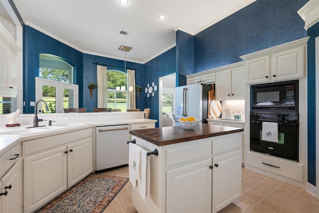 kitchen with sink, butcher block countertops, black appliances, light tile patterned floors, and white cabinets