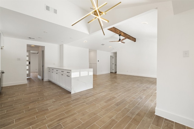 unfurnished living room with ceiling fan with notable chandelier, lofted ceiling with beams, and light hardwood / wood-style flooring