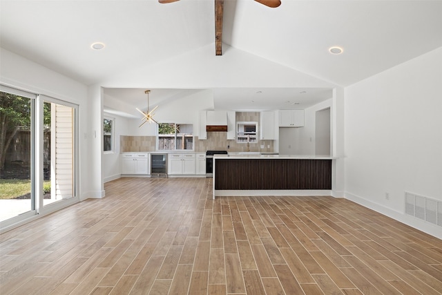 kitchen with light hardwood / wood-style flooring, beverage cooler, white cabinetry, and lofted ceiling with beams