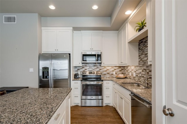 kitchen with light stone countertops, appliances with stainless steel finishes, sink, and white cabinets