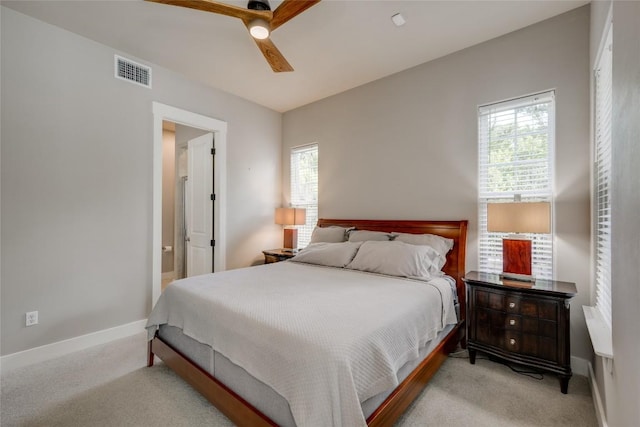 carpeted bedroom with ensuite bathroom and ceiling fan