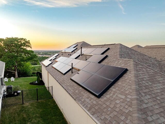 property exterior at dusk with central AC unit, solar panels, and a yard