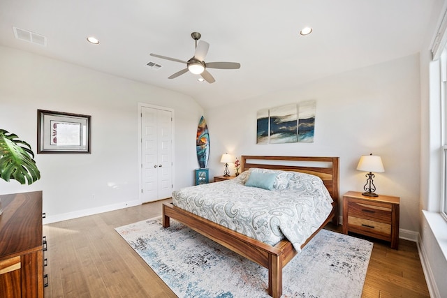 bedroom featuring light wood-type flooring, lofted ceiling, ceiling fan, and a closet