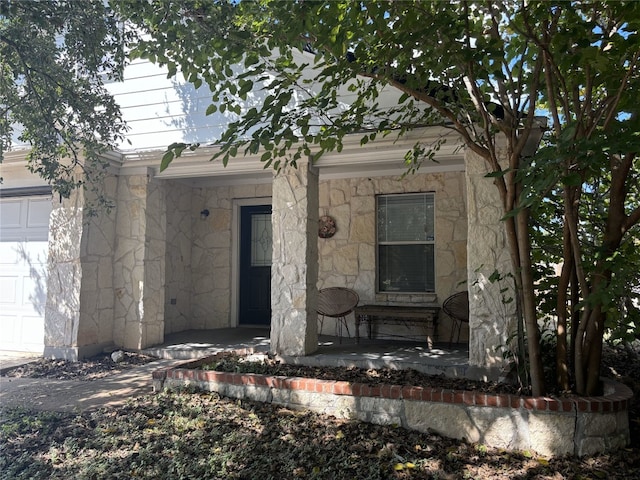 view of exterior entry featuring a garage and a porch