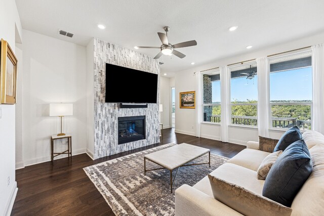 living area with a large fireplace, wood finished floors, visible vents, and a ceiling fan