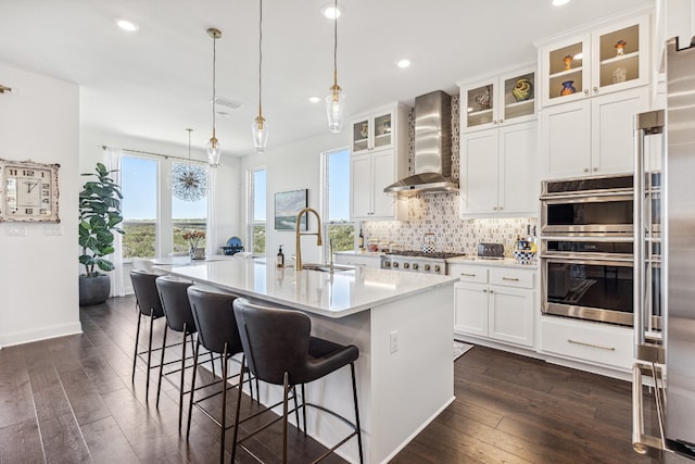 kitchen featuring wall chimney exhaust hood, dark wood-style flooring, a sink, light countertops, and backsplash