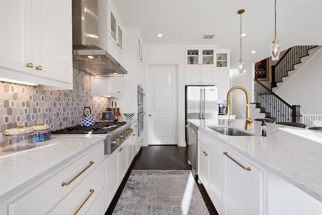 kitchen with stainless steel appliances, a sink, visible vents, backsplash, and wall chimney exhaust hood