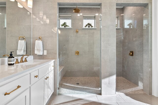 bathroom featuring tile patterned flooring, a tile shower, vanity, and tile walls