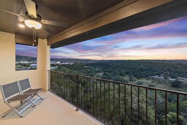 balcony at dusk with a ceiling fan and a wooded view