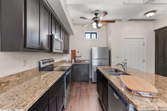 kitchen featuring light stone counters, sink, dark brown cabinets, appliances with stainless steel finishes, and dark hardwood / wood-style floors