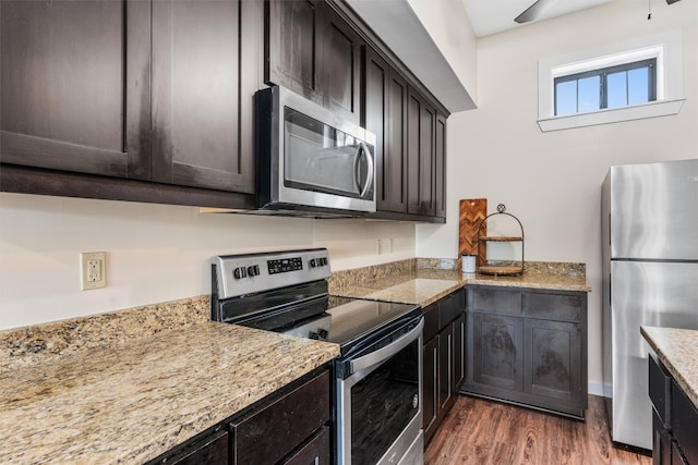 kitchen featuring dark brown cabinets, dark hardwood / wood-style flooring, stainless steel appliances, and light stone counters