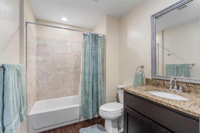 full bathroom with hardwood / wood-style floors, shower / tub combo with curtain, vanity, and toilet