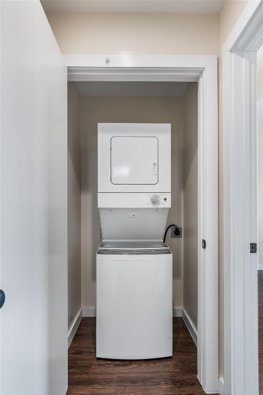 washroom featuring stacked washer / dryer and dark hardwood / wood-style flooring