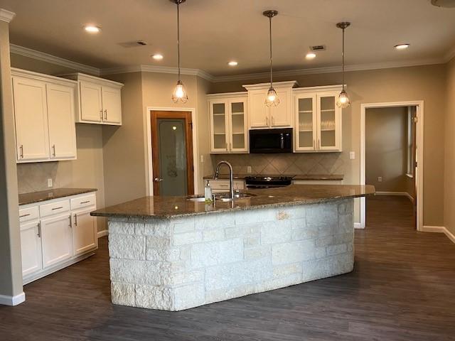 kitchen featuring a kitchen island with sink, white cabinetry, dark hardwood / wood-style flooring, and sink