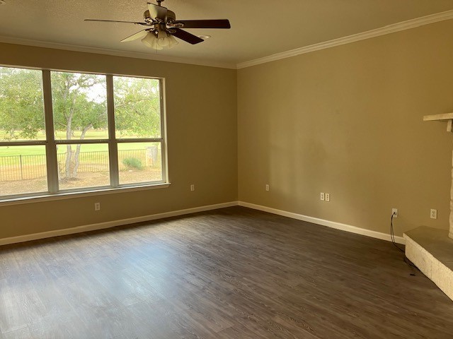 empty room with dark wood-type flooring, ceiling fan, and ornamental molding