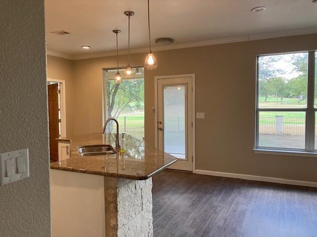 kitchen with dark hardwood / wood-style floors, crown molding, hanging light fixtures, sink, and dark stone countertops