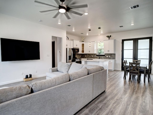 living room with sink, ceiling fan, and light hardwood / wood-style flooring