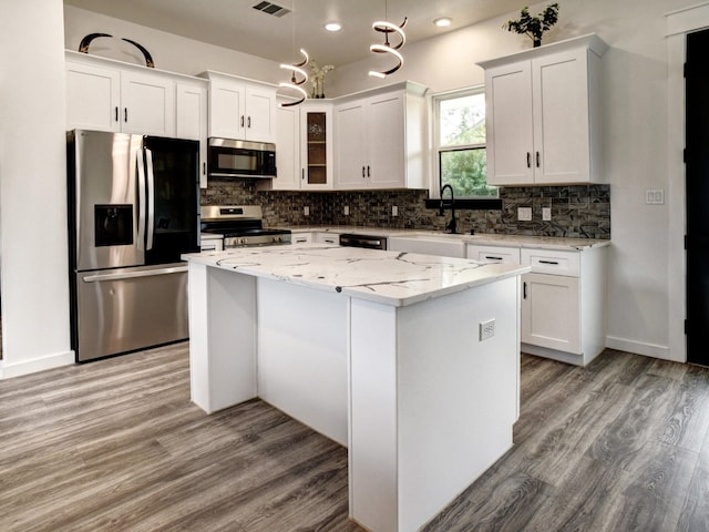 kitchen featuring stainless steel appliances, sink, a kitchen island, white cabinets, and light wood-type flooring