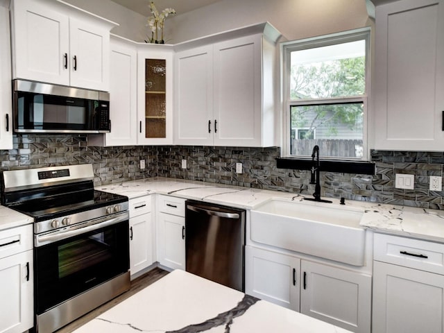 kitchen featuring decorative backsplash, white cabinetry, sink, and stainless steel appliances