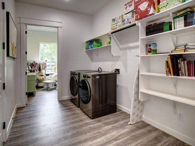 clothes washing area with hardwood / wood-style floors and washer and dryer