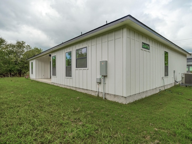 view of side of property with central air condition unit and a yard