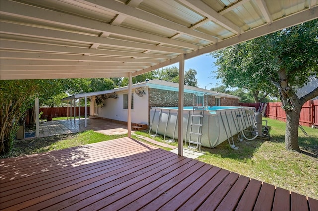 wooden deck featuring a yard, a fenced in pool, and a patio area