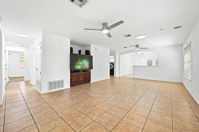 unfurnished living room featuring washer / dryer, plenty of natural light, light tile patterned floors, and ceiling fan