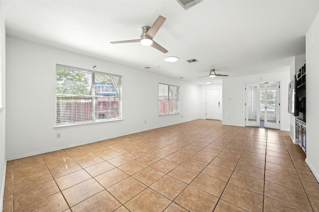 empty room with a healthy amount of sunlight, light tile patterned floors, and ceiling fan