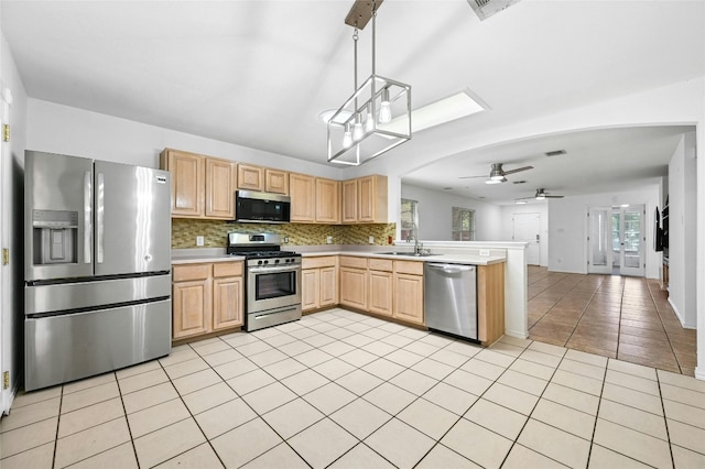 kitchen with ceiling fan with notable chandelier, pendant lighting, light brown cabinetry, appliances with stainless steel finishes, and a wealth of natural light