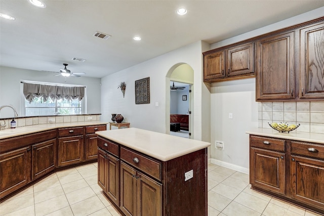 kitchen featuring a kitchen island, backsplash, sink, ceiling fan, and light tile patterned flooring