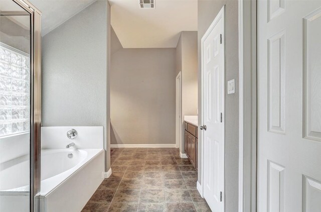 bathroom featuring vanity, a bath, baseboards, and visible vents