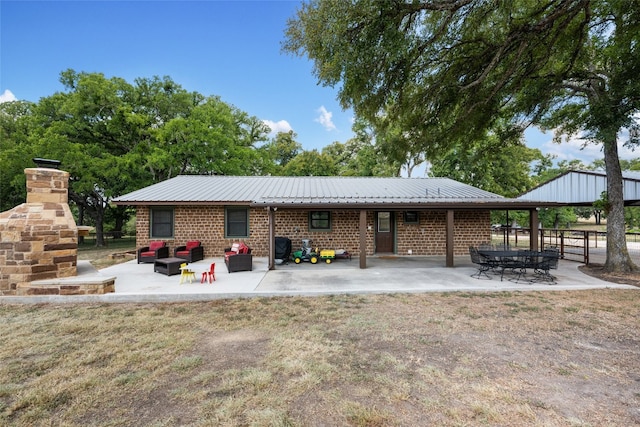 rear view of property with a fireplace, a patio area, and a lawn