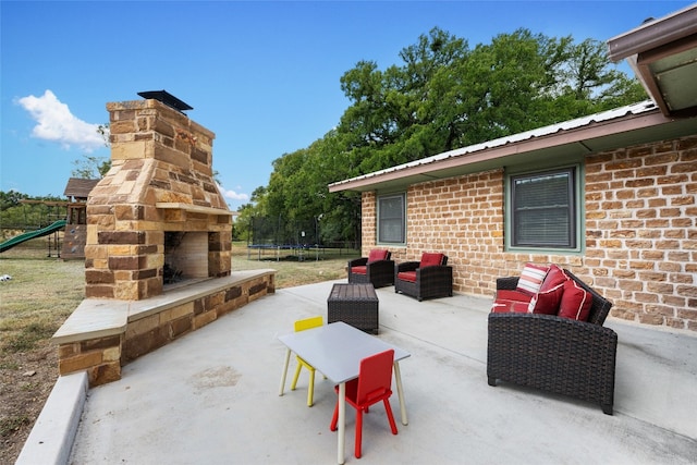 view of patio / terrace featuring an outdoor living space with a fireplace, a trampoline, and a playground