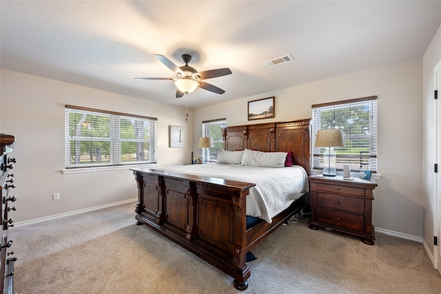 bedroom with multiple windows, ceiling fan, and light carpet