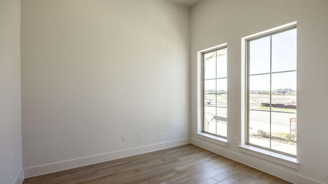 spare room featuring baseboards and wood finished floors