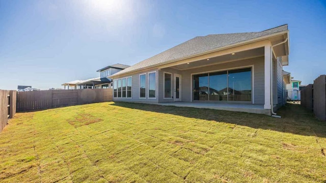 rear view of property featuring a fenced backyard and a yard