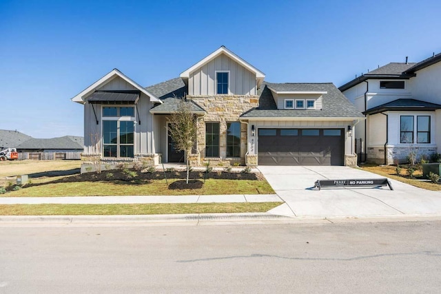 view of front of house featuring roof with shingles, concrete driveway, board and batten siding, a garage, and stone siding