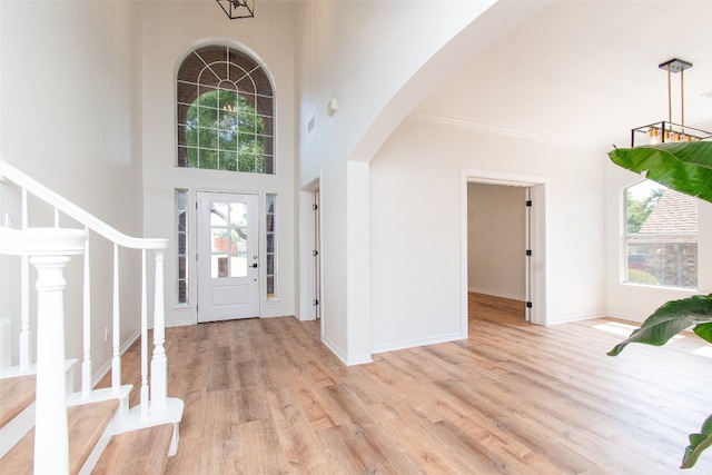 entrance foyer featuring ornamental molding, light hardwood / wood-style flooring, and a high ceiling