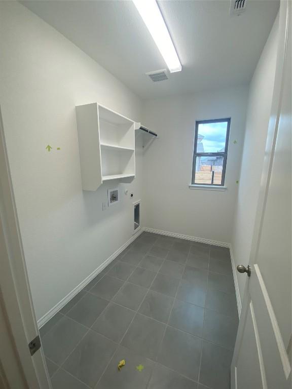 clothes washing area featuring hookup for a washing machine, hookup for an electric dryer, and dark tile patterned flooring