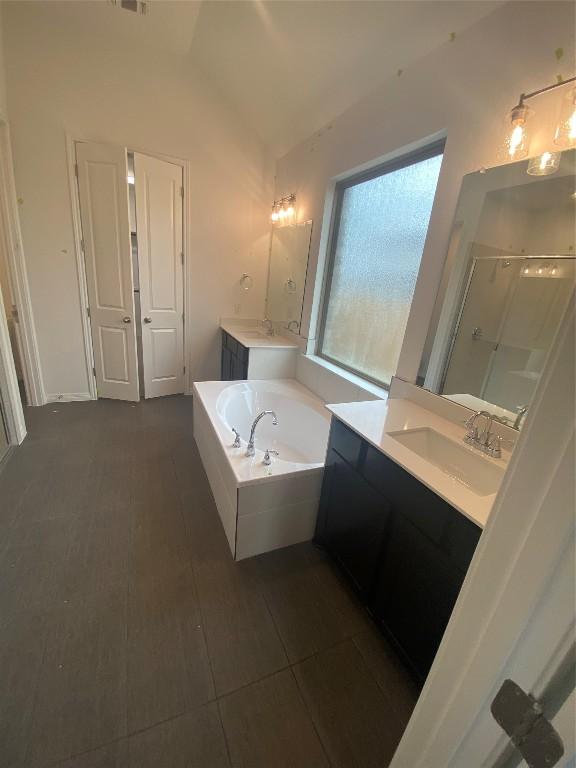 bathroom with vanity, independent shower and bath, and vaulted ceiling