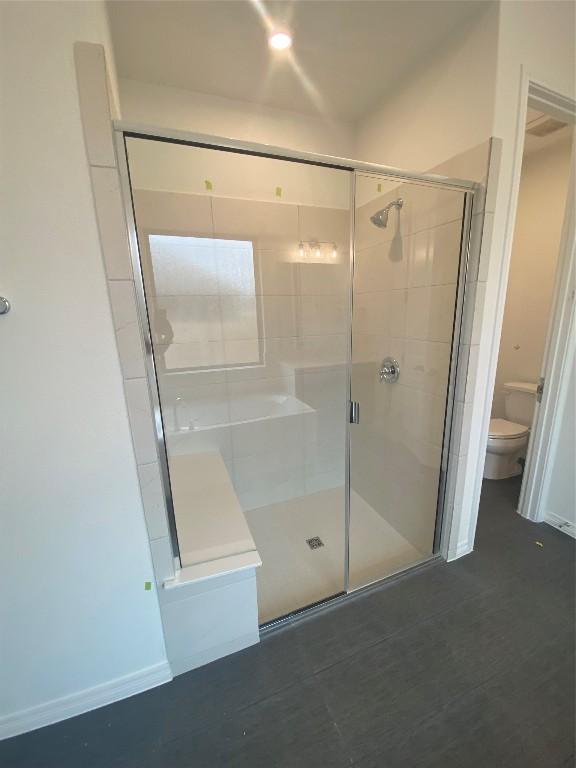 bathroom featuring an enclosed shower and toilet