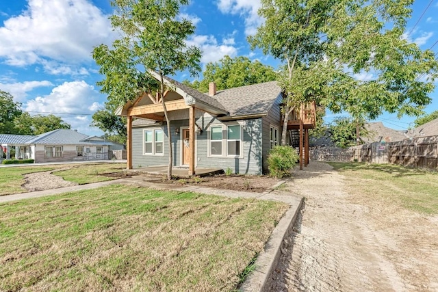 bungalow-style house with a front lawn, fence, roof with shingles, and a chimney