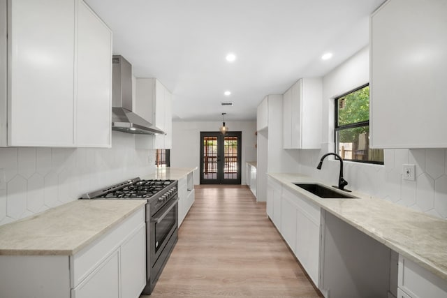 kitchen with backsplash, sink, high end range, and wall chimney range hood