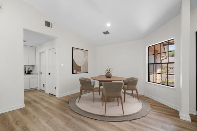 dining room with light wood-type flooring and vaulted ceiling