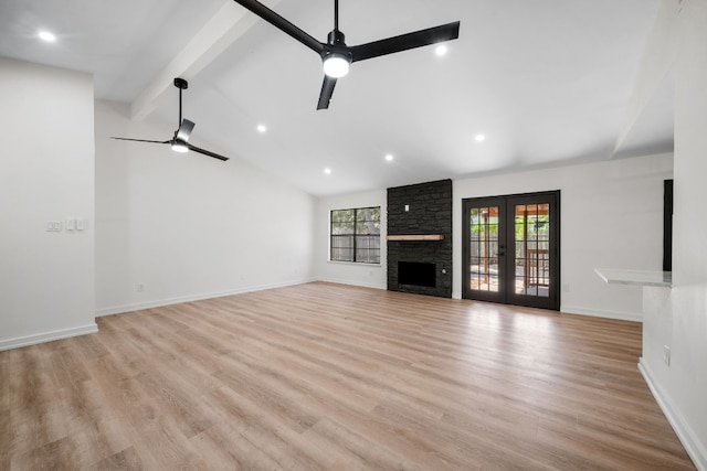 unfurnished living room featuring a stone fireplace, french doors, light hardwood / wood-style floors, ceiling fan, and vaulted ceiling with beams