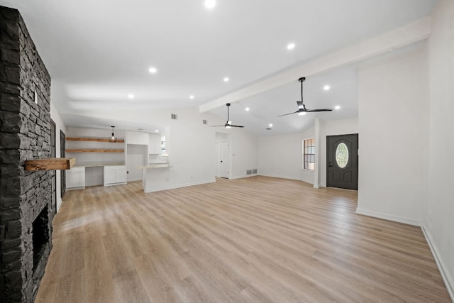 unfurnished living room with light hardwood / wood-style flooring, ceiling fan, lofted ceiling with beams, and a fireplace